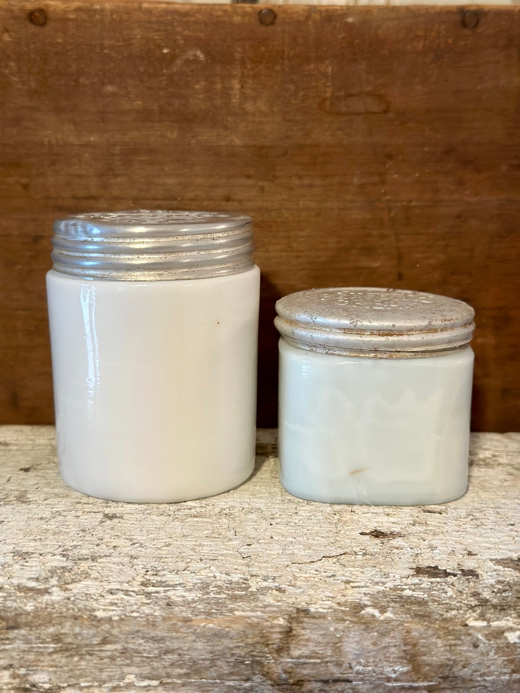 two cold creme milk glass jars, marked lids